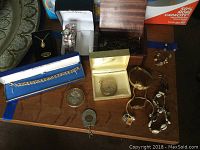 Overhead view of mixed watches and jewelry: fashion watch in white box, link bracelet in box, opal pendant in black box, Hamilton pocket watch in cream box, silver-tone cuff, shell bracelet, earrings