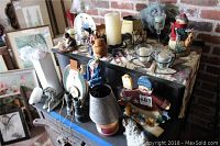 View of assorted home decor including candles, candle holders, snowman decorations, Norman Rockwell decorative plate, and vintage binoculars arranged on a black cabinet top.