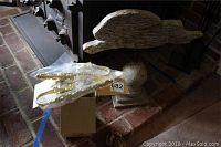 Overview photo showing the brass curtain tiebacks in plastic bags on a cardboard box next to a carved white distressed faux rabbit decoration.