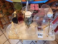 Photo of various glass and colored candle holders, battery operated tealight and candles on a wooden table.