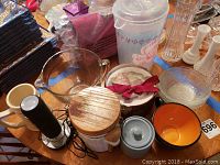 Various kitchenware items including a glass bowl, ceramic cup, plastic container, and an electric wine opener with cord.