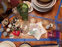 Various sets of salt and pepper shakers, clear glass flower pot holders, a candy dish with lid, and a floral candy dish arranged on a table.
