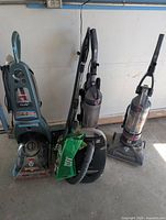Group shot of four vacuum cleaners showing overall condition and accessories