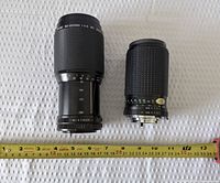 Both lenses side by side with tape measure for scale