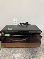 Front view of Panasonic DVD-S53 player stacked on turntable with lid closed