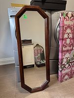 Full view of tall wooden framed mirror standing upright