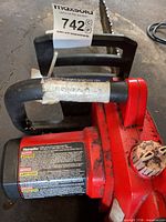 Left side view of Homelite chainsaw showing motor housing, safety decal, bar and chain