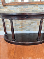 Front view of dark brown demilune console table against wall