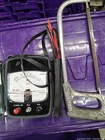 Sanwa DM-1000 tester with leads beside hacksaw inside purple container