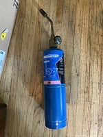 Mastercraft propane cylinder with attached torch head standing upright on hardwood floor