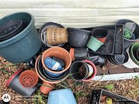 Pile of assorted plastic pots, terracotta pots, seed trays, and wicker basket against wall