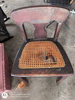 Front view of chair showing broken cane seat and finish wear