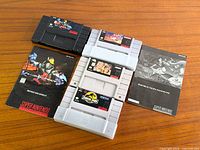 All four SNES cartridges with two manuals displayed on wooden surface