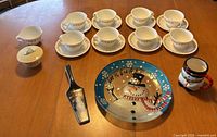 Full set laid out showing teacups, saucers, sugar bowl, snowman plate, cake server, mug