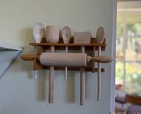 Overall view of wall-mount rack with all seven wooden utensils in place