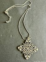Full view of filigree cross pendant on snake chain showing overall design and extender