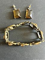 Bracelet in oval form beside two post earrings