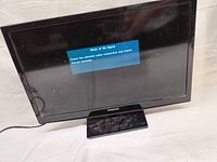 Front view showing screen powered on with 'Weak or No Signal' message and attached stand