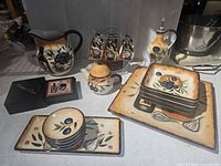 Full view of dinnerware set showing plates, mugs, rack, pitchers, platters and dispenser