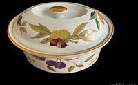 Casserole dish with lid in place showing fruit motifs and gold trim