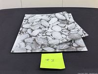 Two square glass plates with pebble design on black surface