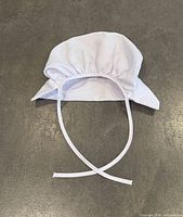 White gathered bonnet-style cap with ties
