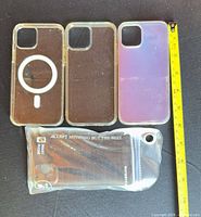 Front view of three phone cases and waterproof pouch with tape measure for scale