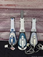 Front view of three handheld vacuums with cords and dock