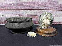 Group view of geode on wood base, dark gray bowl, and small mineral slice