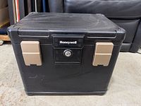 Front view of Honeywell plastic safe showing logo, key lock, tan latches and overall condition