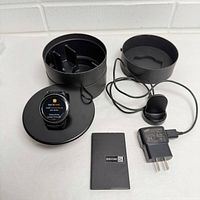 Smartwatch on charging dock with box sections, extra dock, AC adapter, booklet