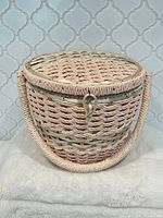 Front view of pink woven straw sewing basket with handle and clasp