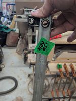 Close-up of sliding jaw head on steel bar with green tape label