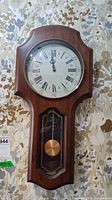 Front view of Elgin wood wall clock showing dial and pendulum window