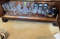 Cabinet shelf with full assortment of glassware, decanter, tumblers, and metal accessories