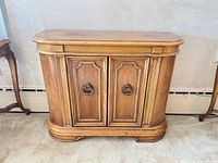 Front view of solid wood cabinet with two paneled doors and brass ring pulls
