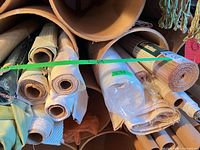 Multiple fabric bolts stored in cardboard tubes showing cream, beige, green and wrapped rolls