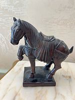 Front view of carved wood horse on base