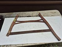 Full view of wooden frame buck saw placed flat on surface