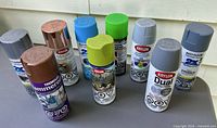 All nine spray paint cans standing on table showing labels and caps