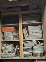 Cupboard of plastic tubs labeled Relays, Breakers & Power, Transformers, etc.
