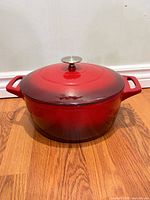 Front view of red enameled Dutch oven with lid showing overall shape and color