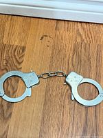 Full view closed handcuffs on wood surface