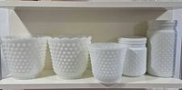 Front view of all five milk glass hobnail pieces on shelf