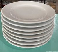 Stack of eight white ceramic plates side view