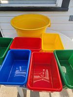 All seven plastic bins displayed: one large yellow tub at back, six small rectangular bins in assorted colors on table