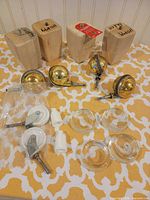 All hardware items laid out: 4 wood legs, 2 brass ball casters, 2 white wheel casters, 4 glass cups, 2 plastic sockets