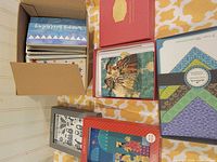 Overview of six boxed card sets inside and beside cardboard box