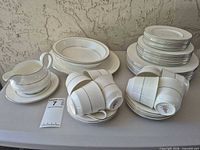 Full lot showing stacked plates, bowls, cups, gravy boat, platter