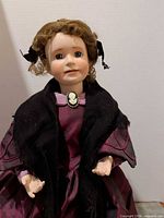 Frontal close-up of doll head, shawl and cameo brooch visible